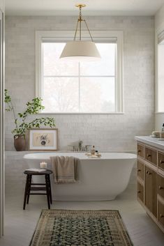 a white bath tub sitting under a window next to a rug