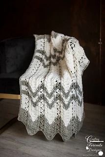 a white crocheted blanket sitting on top of a wooden table next to a black chair