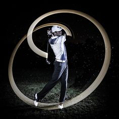 a man swinging a golf club in front of a circular design on the grass at night