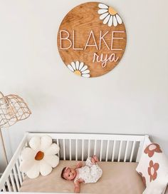 a baby laying in a crib next to a wooden sign