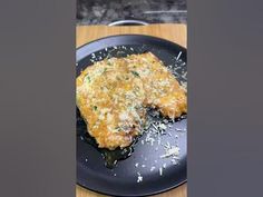 two pieces of fried food on a black plate with grated parmesan cheese