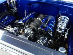 the engine compartment of a blue car with its hood up and it's exhaust system exposed