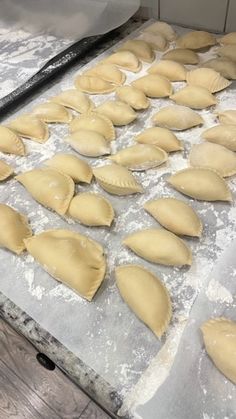 uncooked ravioli being prepared on a baking sheet in an industrial kitchen area