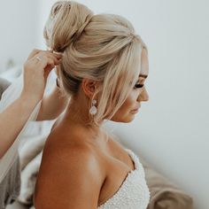 a woman in a wedding dress getting her hair done