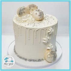 there is a white cake with silver decorations on the top and bottom, decorated with icing