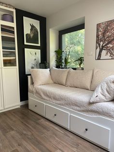 a white couch sitting on top of a hard wood floor next to a book shelf