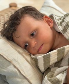 a little boy that is laying down under a blanket