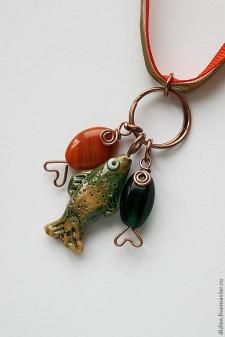 a necklace with a fish charm hanging from it's side on a red cord