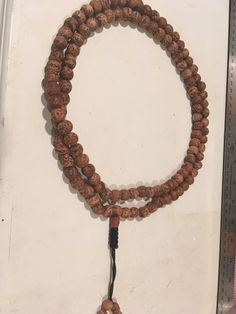 "Bodhi seed mala necklace made of 108 12mm beads with a Bodhi seed guru bead and an adjustable knot that allows you to change the length and tightness of the beads. Bodhi seeds are usually not polished so they are a solid color with small ridges or veins. Bodhi in Sanskrit translates to \"enlightened\" or \"awakened,\" therefore the Bodhi seed means \"enlightened seed.\" Bodhi is also a term in Buddhism to reflect a Buddha's understanding of the true nature of things. Many Buddhist wear the Bodh