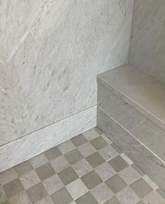 a white tiled bathroom with a checkered floor