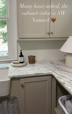 a kitchen with white cabinets and marble counter tops, along with a quote written on the wall