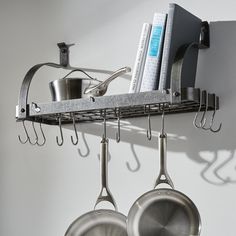 pots and pans hanging from hooks on a wall with kitchen utensils attached to it