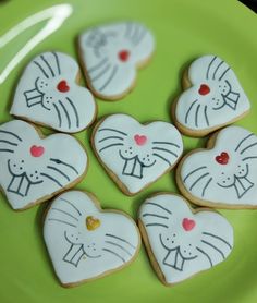 decorated cookies in the shape of cats on a green plate