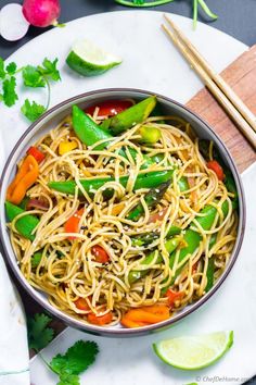 a bowl filled with noodles and vegetables next to chopsticks