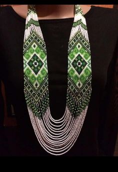 a woman wearing a green and white beaded necklace with matching earrings on her neck