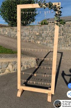 a wooden frame sitting in the middle of a parking lot next to a stone wall