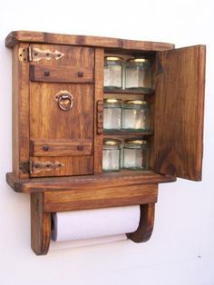 a wooden cabinet with glass jars on the door and shelves above it, hanging from a wall