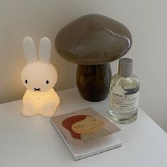 a white table topped with a lamp next to a book and a mushroom shaped object