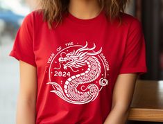 "Unleash Your Inner Dragon in 2024 with this stylish unisex Tee!  Rise to the occasion in this fierce Year of the Dragon t-shirt, featuring a bold and vibrant design that celebrates the power and majesty of this mythical creature. Made with Airlume combed and ring-spun cotton, this tee is incredibly soft and breathable, perfect for both active wear and leisure.  Here's why you'll love it:  * Classic unisex jersey short sleeve tee: This timeless design flatters everyone and pairs perfectly with j New Year Red T-shirt With Graphic Print, Red Graphic Print T-shirt For New Year, New Year Graphic Print Short Sleeve T-shirt, Red Short Sleeve T-shirt For New Year, Dragon Shirt, Mythical Creature, Heather Green, Year Of The Dragon, Tai Chi