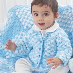 a little boy sitting on top of a couch wearing a blue crochet sweater