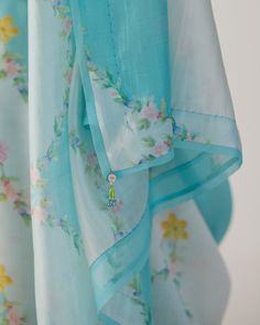 Gulmarg silk sari in stunning shades of blue The rich hues of Kashmiri Mallow flowers printed on luxurious handwoven silk organza, creating an exquisite piece of wearable art. The sari has hand sewn silk organza border. Glass bead tassel add a touch of elegance. We are excited to share that blouse piece with sari has flowers pre placed in sleeve, neck and sleeve making it one of its kind. Explore more ~ www.nadiyapaar.com Collection ~ Lillies of the Valley Silk Organza, Beaded Tassels, Blouse Piece, Glass Bead, Hand Sewn, Wearable Art