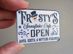 someone is holding up a sticker that says frosty's snowflake cafe open