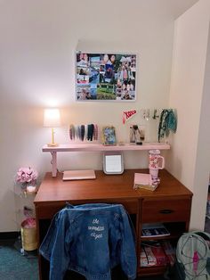 a desk with a jacket on it next to a lamp and pictures hanging on the wall