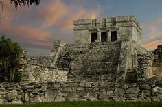 an old stone structure sitting on top of a lush green field under a cloudy sky