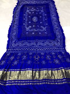 Traditional Pattern Gaji Silk Bandhani Dupatta - 80 Grams Pure Silk This dupatta is made to order, meaning it is created specifically for each individual customer. Therefore, the photo provided is just an example and design variations may occur.  ➢ Manufactured by Indian artisans in Kutch. ➢ Dupatta is non-ironed to leave the original crinkly effect. ➢ Colour of the product may vaguely vary due to the photographic lighting. ➢ The pattern may vary slightly because it is handmade with tie and dye Blue Unstitched Ceremonial Traditional Wear, Ceremonial Blue Lehenga With Traditional Drape, Blue Festive Ceremonial Lehenga, Blue Traditional Wear With Dupatta For Ceremonial Occasion, Blue Lehenga With Traditional Drape For Ceremonial Occasions, Ceremonial Blue Dupatta With Zari Work, Blue Ceremonial Dupatta With Traditional Drape, Blue Ceremonial Dupatta In Traditional Drape, Blue Traditional Drape Dupatta For Ceremonial Occasions