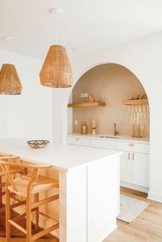 an instagramted photo of a kitchen with white cabinets and wooden chairs, hanging lights over the island