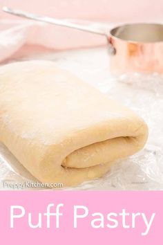 puff pastry sitting on top of plastic wrapper next to a measuring cup and pan