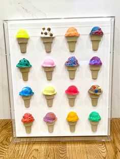 an ice cream display is displayed in a clear frame on a wooden floor with white walls and wood floors