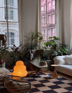 a living room filled with furniture and lots of plants on the windows sills