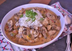 a white bowl filled with rice and meat covered in mushroom gravy on top of a table