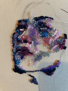 a woman's face made out of beads and sequins on a white surface