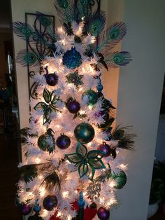 a white christmas tree decorated with peacocks and ornaments