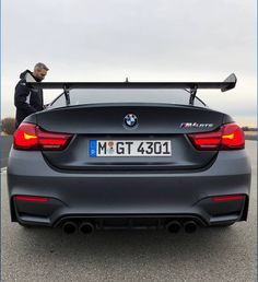 a man standing next to a gray bmw car