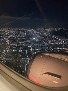 the view from an airplane window shows city lights and buildings at night in the distance