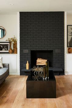 a living room with a couch, coffee table and fire place in front of a black brick wall