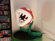 an inflatable mushroom with its mouth open on top of a green table next to a book shelf