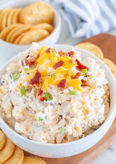 a white bowl filled with chicken salad next to crackers