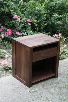 a small wooden table sitting in front of some flowers