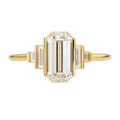 an emerald cut diamond ring with three baguets in yellow gold and white diamonds