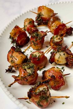 bacon wrapped scallops on a white plate with parsley sprinkled on top