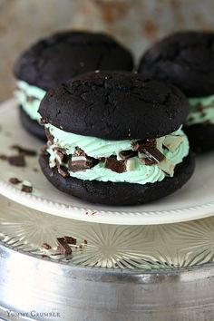 three cookies with mint cream and chocolate chips are on a plate next to a silver platter