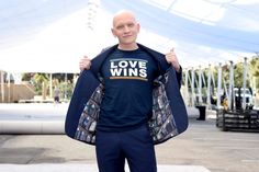 a bald man is holding up his love wins t - shirt