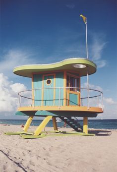 a lifeguard tower on the beach with surfboards under it