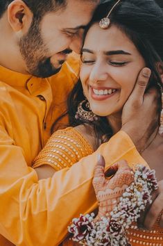 a man and woman hugging each other with their hands on the chest, both smiling