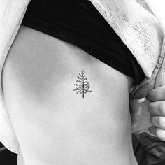 a small pine tree tattoo on the back of a woman's left thigh,