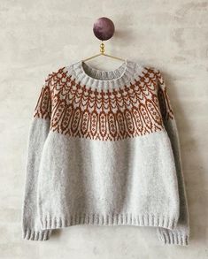 an orange and white sweater hanging on a wall